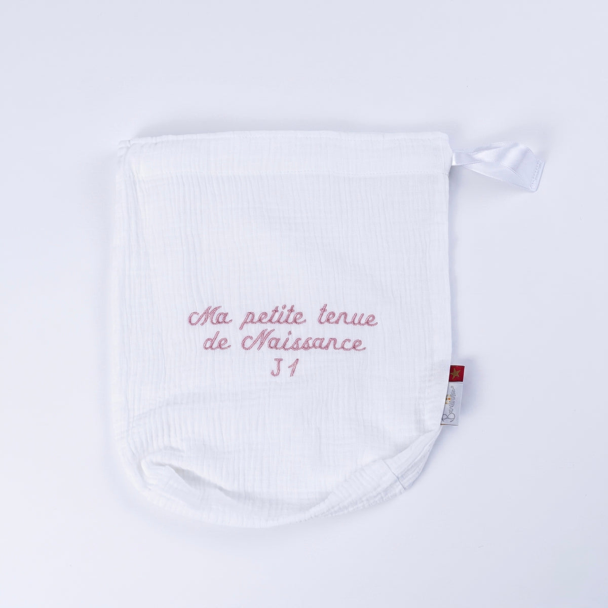 Pochon de naissance en gaze de coton blanc brodé rose J1 sur fond blanc épuré.