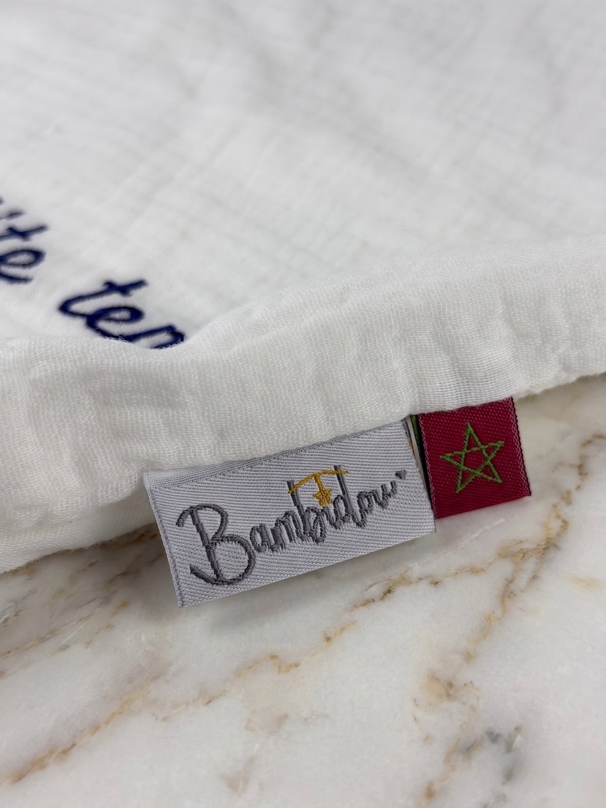 Zoom sur étiquette Bambidou et drapeau marocain sur fond marbre.