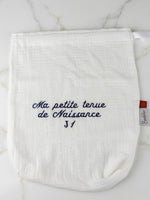 Pochette naissance J1 en gaze de coton blanche sur marbre, broderie bleue.